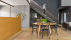 house contemporary Living area architectural photograph showing hydronic heating trench product in front of quality timber finish kitchen island with timber grate matching timber flooring with view of lady walking down stairs in background dining table and couch seating