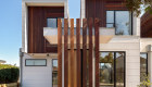 exterior photography of West Footscray townhouse new development, architectural design, iron bark wood features, white facade, roger thompson photography, blue sky,