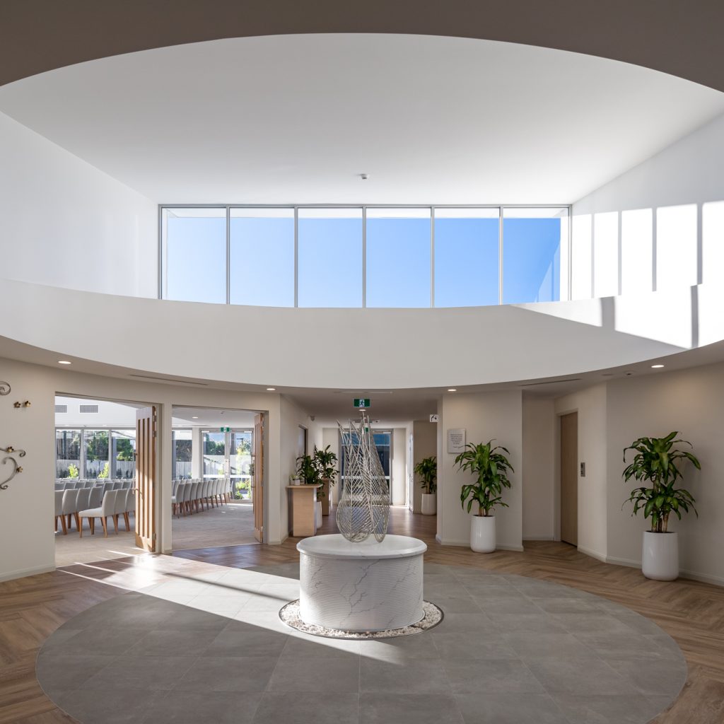 Le Pine and white lady funeral home circular grand hallway with water feature sculpture looking in to chapel internal photo by Roger Thompson Photography Melbourne